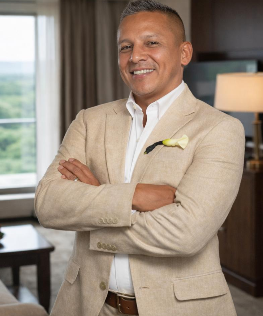 Alberto Gerardini, Senior Sales Leader, smiling in a beige suit with arms crossed in a professional office setting